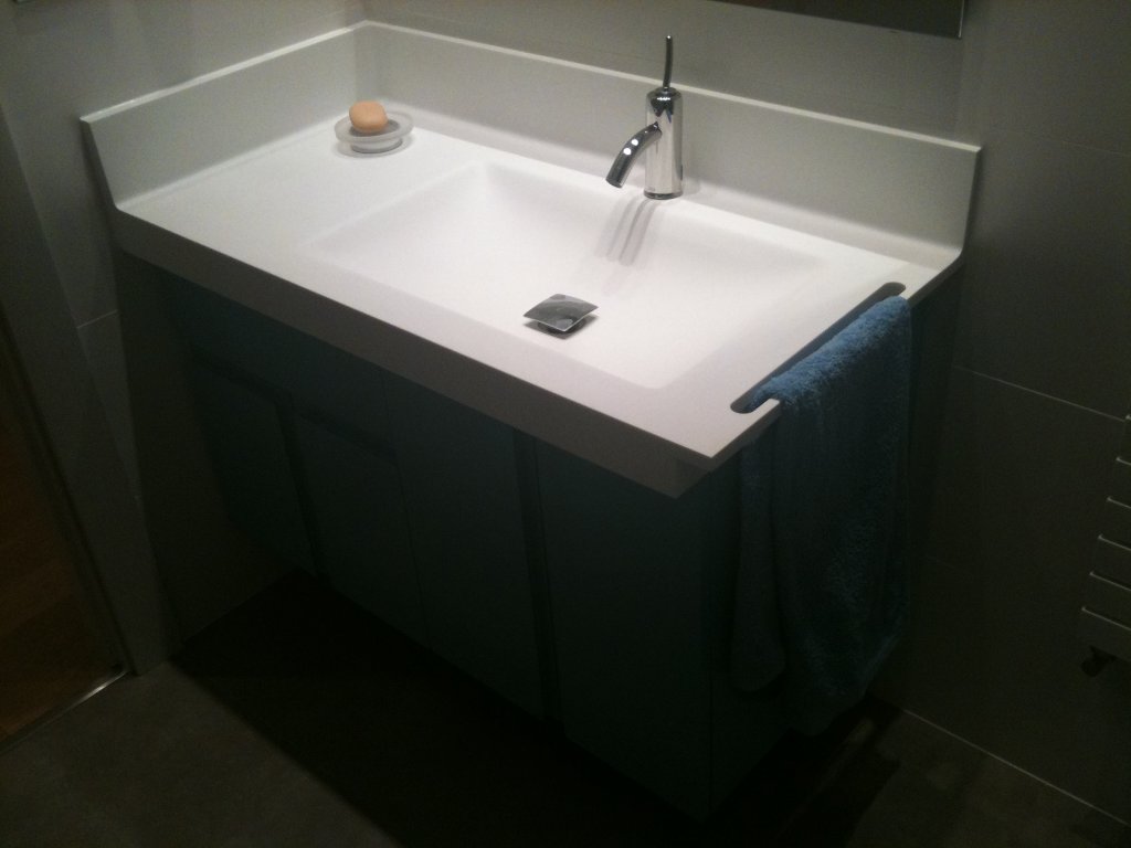 Encimera termoformada de lavabo integrado y copete curvo sin siliconas. Mueble de baño en acabado lacado con tiradores fresados.
